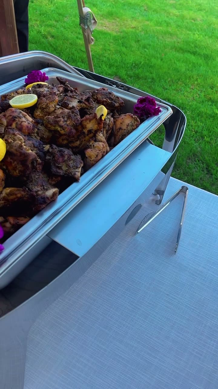 Grilled jerk chicken garnished with lemon and flowers
