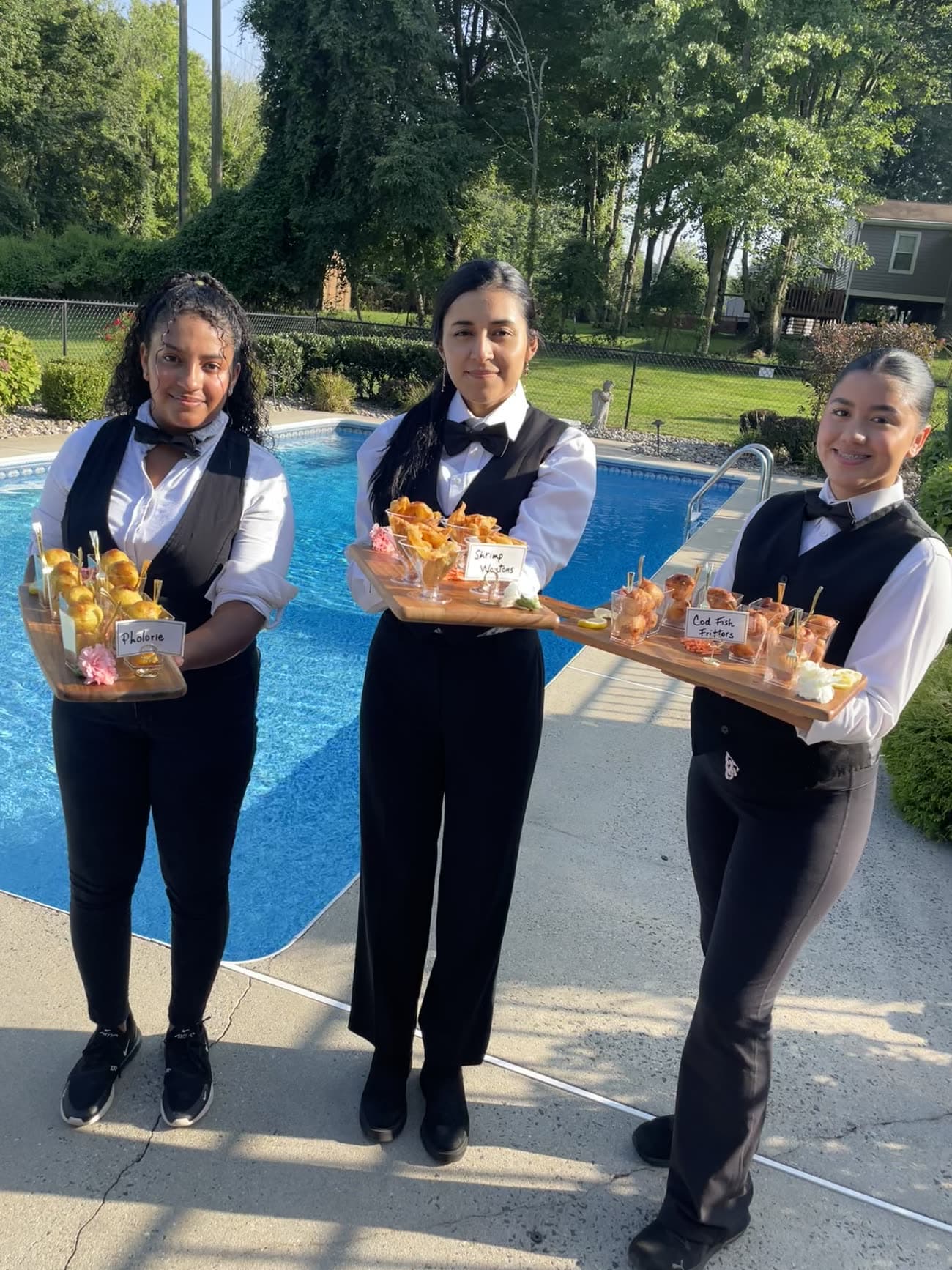 Servers presenting trays of canapés poolside